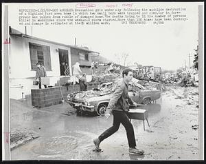 Evacuation gets underway following the mudslide destruction of a Highland Park area home in which two small boys were trapped and died. Car in foreground was pulled from rubble of damaged home. The deaths bring to 11 the number of persons killed in mudslides since the week-old storm started. More than 100 homes destroyed and damage is estimated at the $5 million mark.