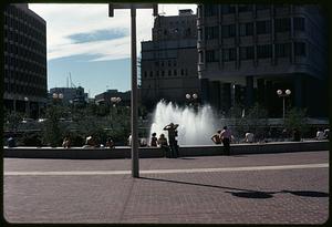 People sitting around Boston City Hall plaza fountain