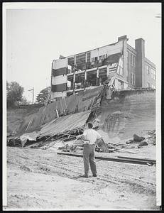 Putnam School Wrecked- The west wall of the Trade School at Putnam, Conn., lies in ruins after Quinebaug river tore through, cutting the town in two. Dams bursting upstream unleashed torrent. Putnam is where magnesium plant blew up, hurling blazing barrels of explosive into waters.