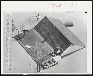 Flood Escape hatch--A family near New Albany, Ind., takes clothing and furnishings through a hole in the roof, while evacuating their farm home as flood waters rose to rooftop level today.