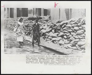 Sandbagged Stores Two girls trudge through downpour in center of city today as stores are sandbagged against onslaught of hurricane Edna. Downtown Providence was flooded by hurricane Carol 11 days ago.