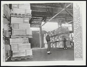 New York -- Spuds Stalled By Dock Walkout -- Military police men stand guard over crates of potatoes stacked on pier at the Army Port of Embarkation in Brooklyn. Loading of the vegetables aboard a ship in background has been halted by a wildcat strike of longshoremen. The potatoes are intended for American servicemen on duty overseas.