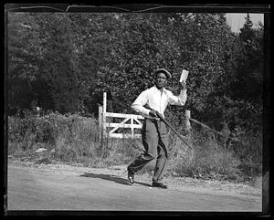 A man holding a rifle in one hand and a piece of paper in the other