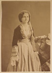 Studio portrait of woman in traditional Greek dress and hat with long tassel