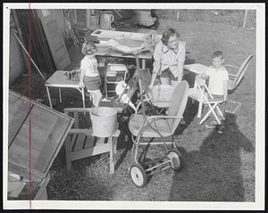 Welcoming The Sun with an assortment of furniture and implements from the cellar yesterday were Mrs. Thomas Foley of Spring street, Framingham, and her children, Mary and David. It was drying-out day in much of Greater Boston.