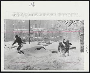 Chicago - Underneath The Feet, Rooftops of Cars -- Youths toss snowballs while crust of drifts keeps them at car rooftop level in Chicago storm today. Action came in vicinity of Kenmore and Foster Ave. in Chicago's northwest side.