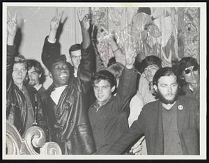 A group of young men hold up peace "V" sign