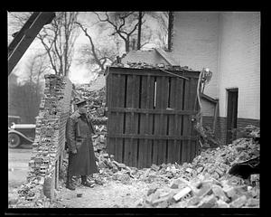 Policeman standing by debris of the remains of a wall