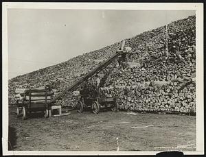 One of The World's Biggest Woodpiles! If you were a youngster again and had to chop the kindling before you went out "for that fun" how would you like to meet up with this woodpile. It's at Damascus, Virginia, and one of the largest in the world since it is added to as fast as the dried wood is used. The machine in the foreground is a pulpwood stacker at work doings it's part in converting the woodpile into paper.
