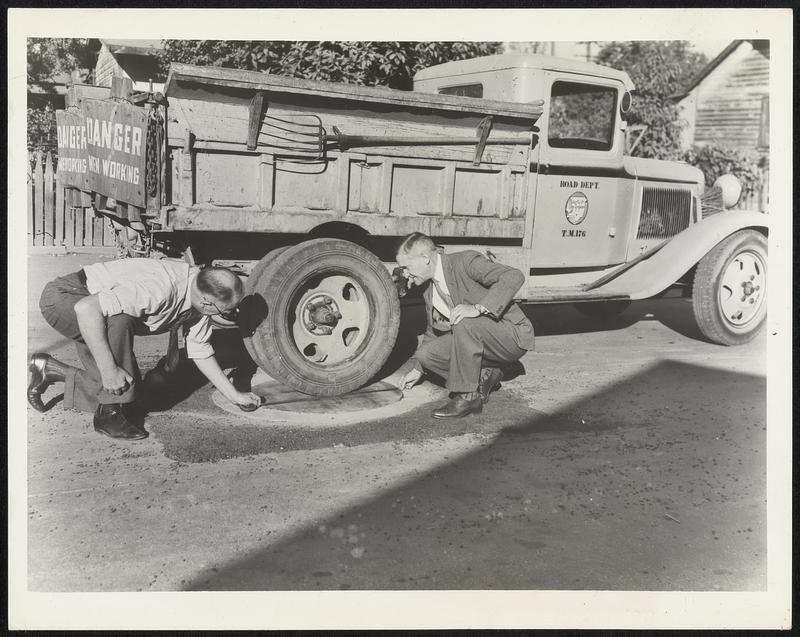 At Last - Wooden Manhole Cover To determine if their newly designed wooden manhole cover will carry traffic weight satisfactorily, two Los Angeles county officials check the measurements of the street lid. They are Col. Carl. H. Reese (left) superintendent of the maintenance department, and Alfred Jones, surveyor. County specifications require the cover to be pressure-treated with Eithe Wolman salts or creosote.