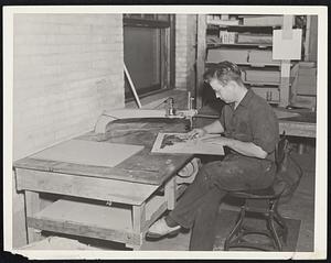 Making the "negative". An operator tacks the contour map to a sheet of cardboard and starts by cutting out the highest contour sections with a special jig-saw that cuts in all directions. The first cardboard will contain only a few holes, representing mountain tops. The contour map is then tacked to another cardboard and the next contour level cut our. When all the cardboards are piled together they form a reverse upside-down model of the section.