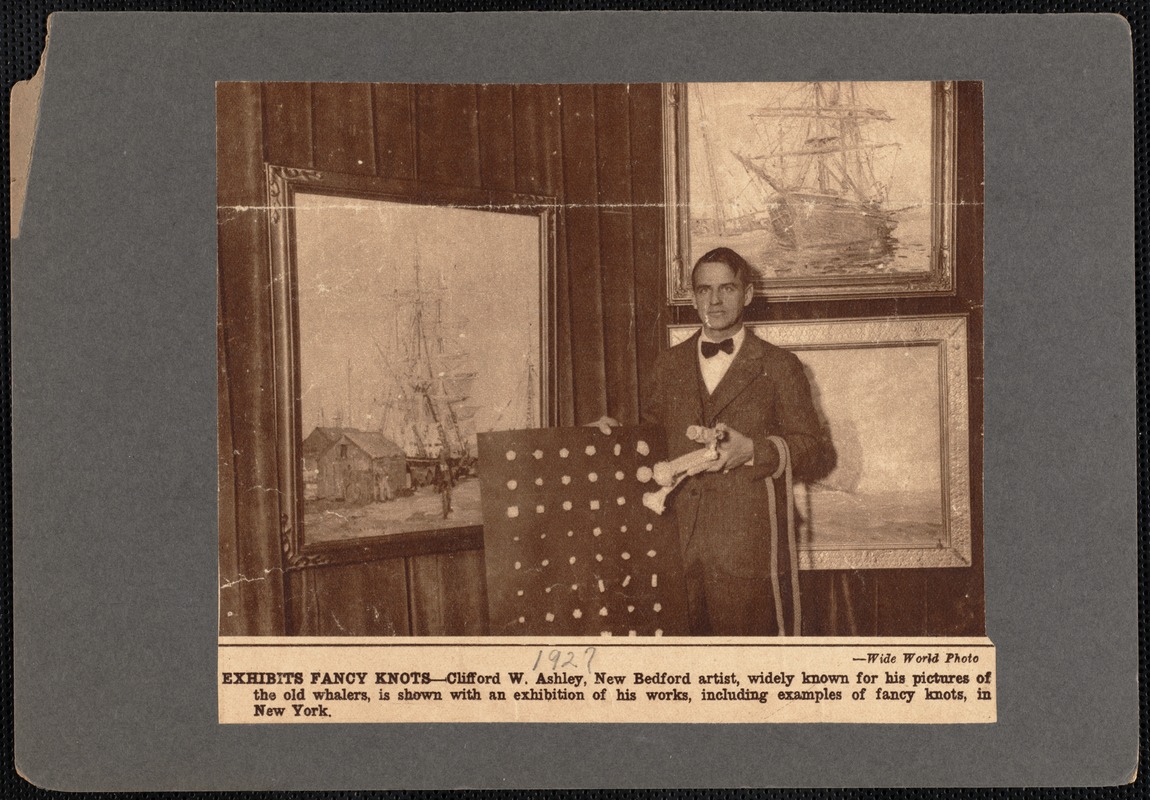 Painter Clifford Ashley in front of New York exhibit of his works and holding board containing different types of knots