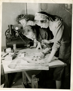 Woman using an airbrush while two people watch