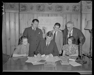 Governor Saltonstall signing a document as others watch