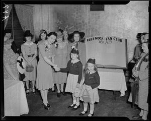 Ruth Moss poses with children in front of oversize Ruth Moss Fan Club register
