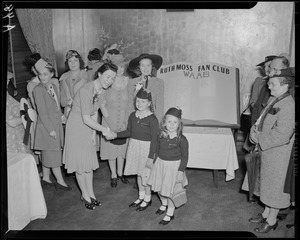Ruth Moss poses with children in front of oversize Ruth Moss Fan Club register