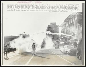 Berkeley, Calif: Teargas cannister leaves a trail of gas as it arches towards police at Right. Police had just laid down a massive teargas barrage 2/20, along Bancroft Ave., in one of many efforts to quell the worst outbreak of violence in a month at this embattled University of California. At least a dozen persons were arrested, 2 police vans turned over & undreds of demonstrators and newsmen had their eyes irritated by the repeated barrages of gas.