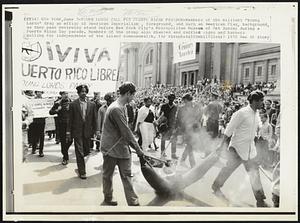 New York, 7-Young Lords Call For Puerto Rican Freedom -- Members of the militant "Young Lords" drag an effigy of American Imperialism, foreground, and burn an American Flag, background, as they pass reviewing stand before New York City's Metropolitan Museum of Art Sunday during a Puerto Rican Day parade. Members of the group also chanted and carried signs and banners calling for independence of the island commonwealth. Demos. Misc.