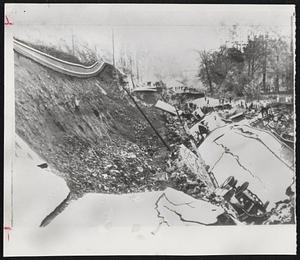 Norwegian Landslide-Overturned vehicles lie alongside a shattered concrete highway after a landslide near Oslo, Norway. A section of railway track, torn loose in the downpour, hangs suspended over the embankment. Two persons, reportedly passengers aboard a bus caught in the slide, were missing after the rain of earth and rocks.