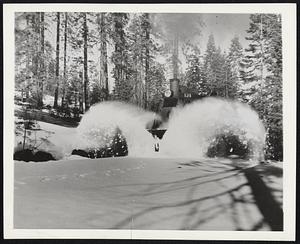 Wartime Logging. A bucking plow with blade throws chunks of wet snow. A few seconds after this shot was made the photographer, whose tracks may be seen on snow at left, was hit by on of these chunks and received injuries requiring a rush trip to Westwood Hospital.