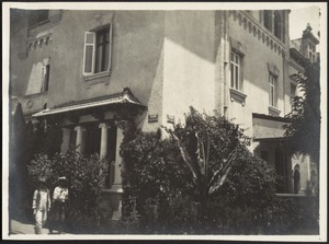 Corner view of 3-story building, two men walking in foreground