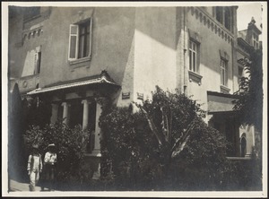 Corner view of 3-story building, two men walking in foreground