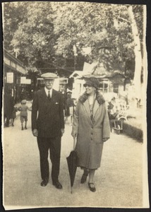 Man and woman walking down busy village street, possibly in Europe