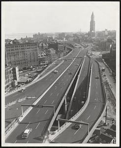The Boston Central Artery, (shown from the Industrial Building next to North Station,) showing the divided highway as it extends beyond Haymarket square to the Sumner Tunnel area now open for traffic from Mystic River Bridge southbound; and from Leverett circle, near Museum of Science, which is open for both southbound and northbound traffic. Commissioner John A. Volpe announced that it is anticipated that two-way traffic would be opened on the section from the Mystic River Bridge during the middle to latter part of December.