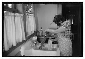 A woman doing laundry at a sink with a washboard