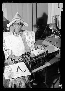 Jack Miller sits at typewriter wearing costume made of newspaper