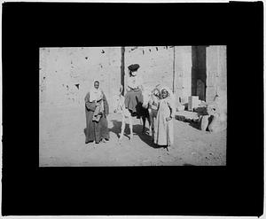 Woman on donkey flanked by two others standing