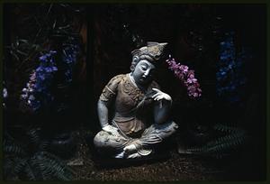 Seated Buddha statue on grass among flowers