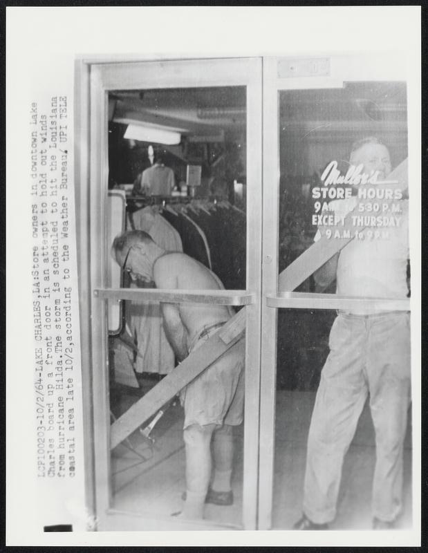 Lake Charles, LA: Store owners in downtown Lake Charles board up a front door in an attempt to hold out winds from hurricane Hilda. The storm is scheduled to hit the Louisiana coastal area late 10/2, according to the Weather Bureau.