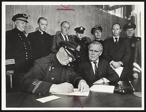 Daniel J. Sweeney, president of the Boston Patrolmen's Assn., sings new 14-month contract as Mayor Kevin H. White looks on. Also observing ceremony are, standing, from left: Supt. William Bradley, Rev. James Lane, Police Commr. Edmund McNamara, Patrolman Paul Whelan, Supt. William Taylor, Atty. Robert Wise and Patrolman Paul Nelson.