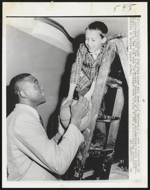 PInt-sized Paul Kern, 6, of Westwood, N.J., uses a stepladder to an autograph 12/29 from 6-foot, 51/2 - inch University of Michigan All-American Cazzie Russell. Russell is in New York with the Michigan team to play in the E.C.A.C. Holiday Basketball Festival at Madison Square Garden.