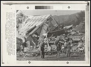 This is the Yellow printer showing rescue operations at the Veterans Administration hospital in Sylmar following today's earthquake. Men in foreground have blue jackets and yellow helmets and grass is green. Wall at upper left is white with blue windows. Broken wall facing camera is beige.