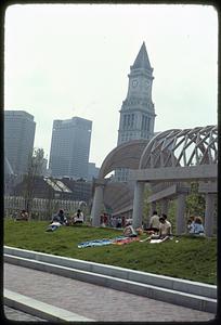 People sitting on grass, Christopher Columbus Park, Custom House Tower in background