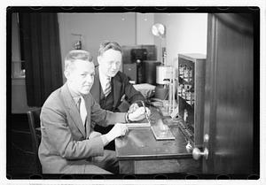 A boy sitting next to a man using an unidentified device