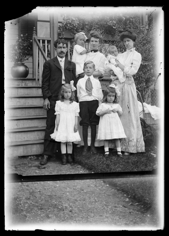 Family group (standing) outdoors in front of house