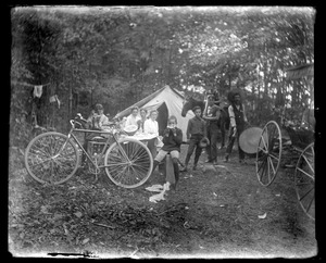 Camping out - family group amidst tent, bicycle, & carriage etc.