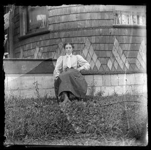Young woman sitting outdoors in front of house