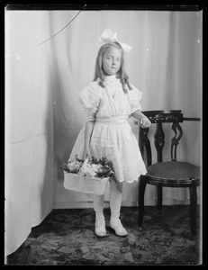 Young girl with basket of flowers, studio portrait