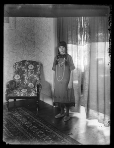Girl with many necklaces standing by window, interior (Indian costume)