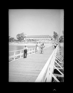 People walking on a wooden boardwalk with buildings in the distance