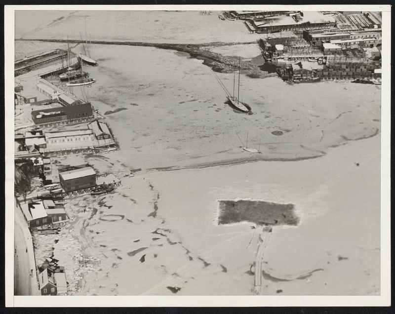 Gloucester Harbor Becomes Skating Rink. Gloucester Mass: This airplane view shows the rocky neck of Gloucester Harbor frozen over solid with a square cleared on the ice for skating. Close to the skating rink can be seen ships frozen in the ice.