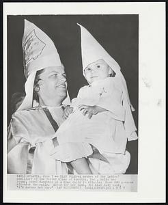 Klan Folk-- A member of the ladies' auxiliary of the United Klans of America, Inc., holds her young, robed daughter at a Klan rally in Atlanta. Some 600 persons attended the rally. Asked for her name, the Klan lady said, "I'd rather not say."