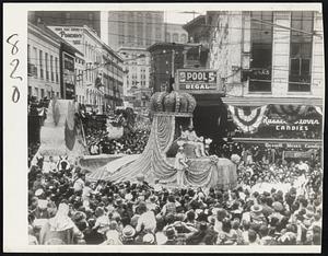 King "Rex" Leads Mardi Gras Parade through throngs of merry-makers in New Orleans streets. Here the royal float turns from St. Charles avenue into Canal street.