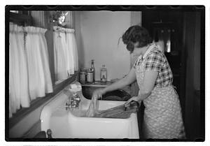 A woman doing laundry at a sink with a washboard