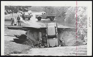 Through the Highway at Springfield went this car when the vehicle's weight broke through the surface which had been undermined by more than 32 hours rain. The driver climbed out unhurt. This was typical flood scene as roads were washed out all over the state.