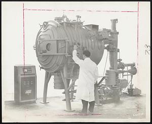 Uranium Furnace -- William O'Toole, assistant assembly foreman at the Kinney Vacuum Division of the New York Air Brake Company, stands before a 300-pound Kinney uranium furnace system manufactured for the D.E. Makepeace Company of North